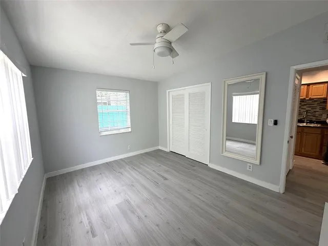an empty room with wooden floor fan and windows