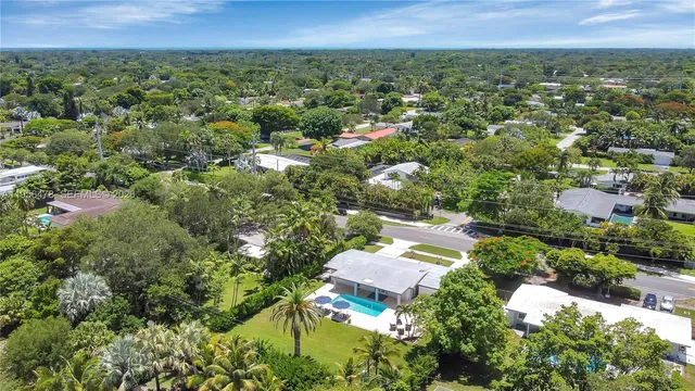 an aerial view of residential houses with outdoor space and trees
