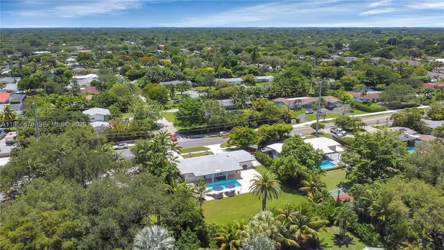 an aerial view of residential houses with outdoor space and trees