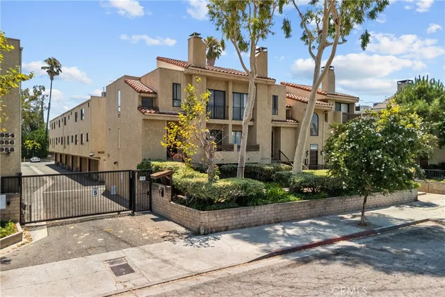 a view of a white building among the street with palm trees