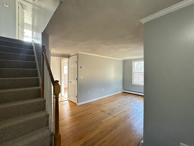 a view of an empty room with stairs and wooden floor