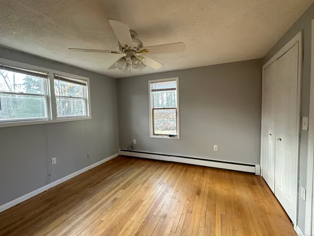 a view of room with window ceiling fan and hardwood floor