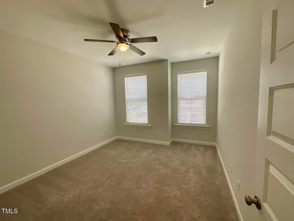 an empty room with windows and fan