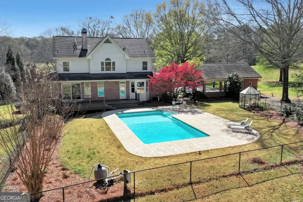 a view of swimming pool with outdoor seating and trees in the background
