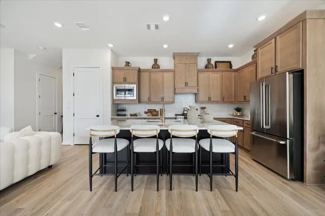 a kitchen with stainless steel appliances kitchen island granite countertop a table chairs and a refrigerator