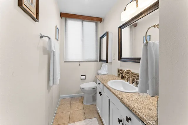 a bathroom with a granite countertop sink a toilet and a mirror