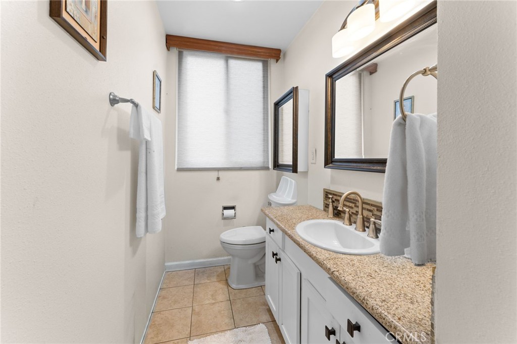 6979 Palm Court Riverside, CA 92506 - Photo 20 of 28 a bathroom with a granite countertop sink a toilet and a mirror