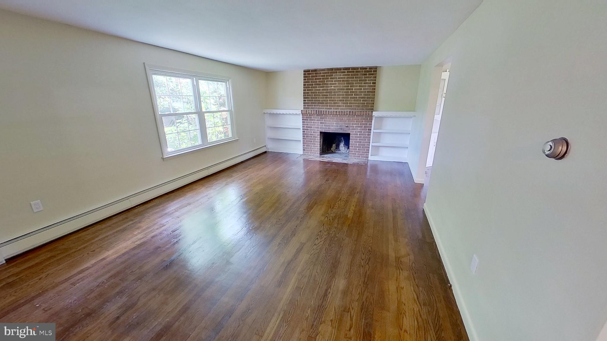 2174 South Queen Street, Unit A York, PA 17402 - Photo 2 of 9 an empty room with wooden floor a fireplace and windows