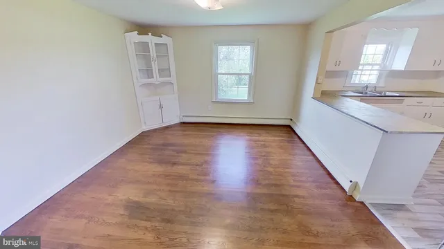 an empty room with wooden floor and windows