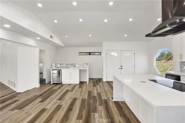 a large white kitchen with a lot of counter space and wooden floor