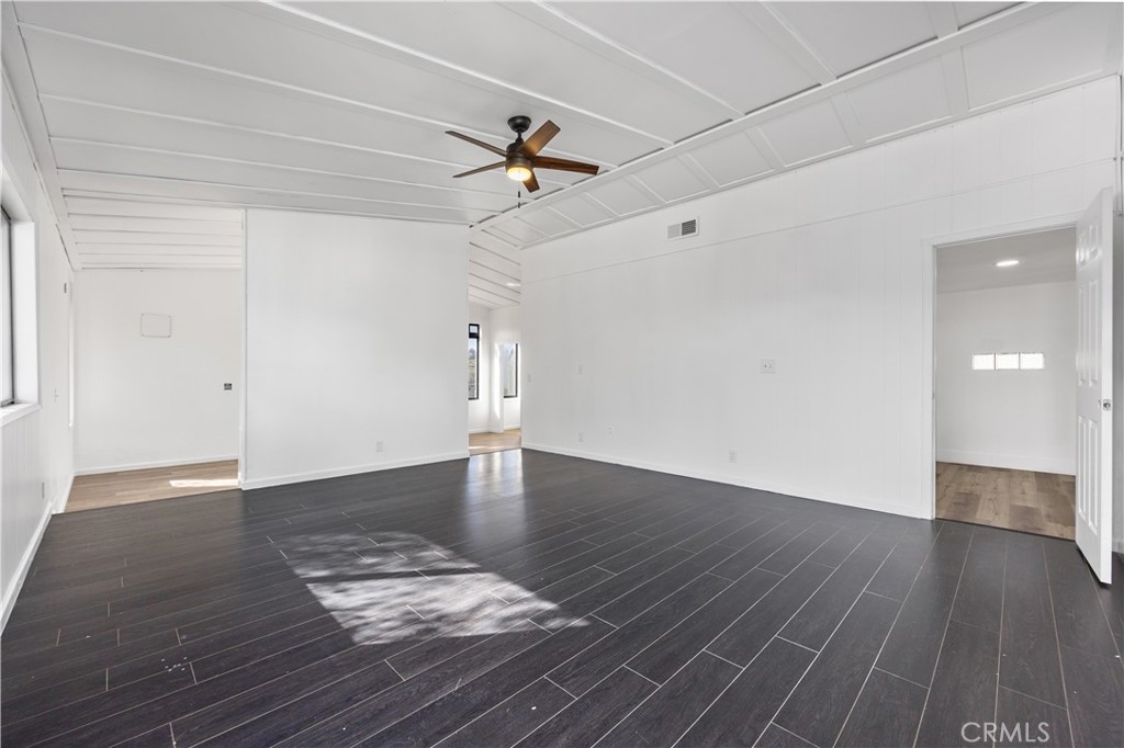 29300 Elkhorn Place Tehachapi, CA 93561 - Photo 18 of 47 an empty room with wooden floor chandelier fan and windows