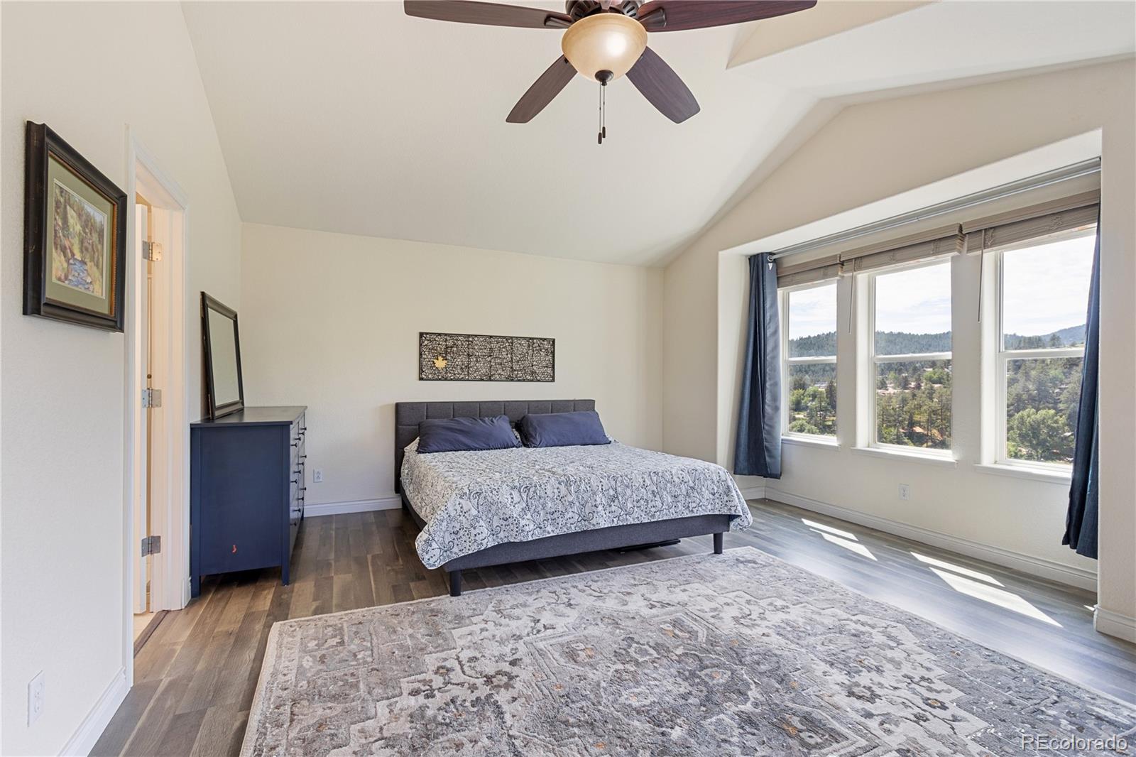 3345 Russell Gulch Road, Unit A Evergreen, CO 80439 - Photo 17 of 34 a spacious bedroom with a large bed and a chandelier