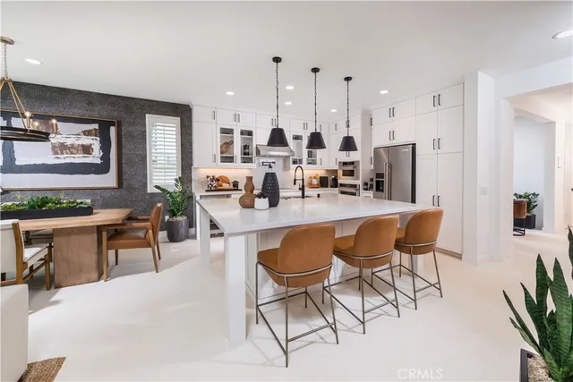 a dining room with stainless steel appliances kitchen island granite countertop a table chairs and a refrigerator