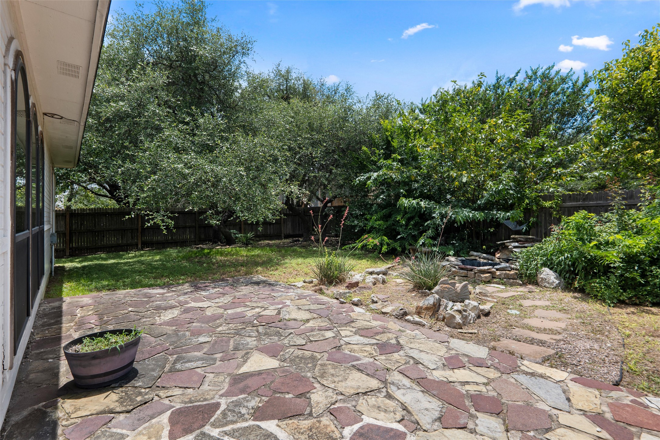 7000 Colberg Court Austin, TX 78749 - Photo 37 of 40 A spacious backyard retreat features a flagstone patio and verdant landscaping, enclosed by a privacy fence.
