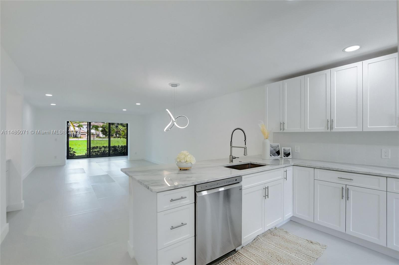 a kitchen with white cabinets a sink dishwasher and white countertops with wooden floor