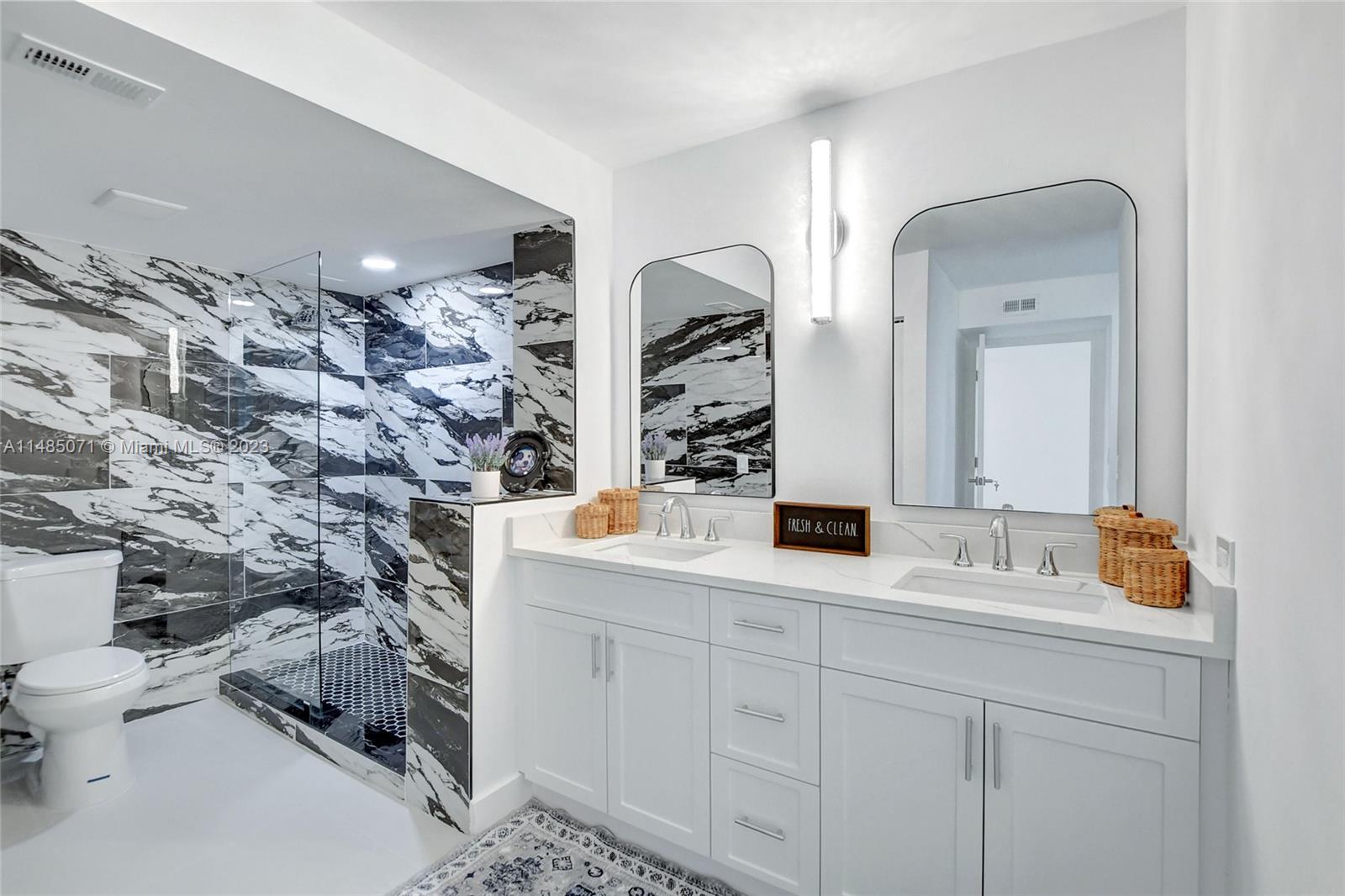 9264 Vista Del Lago, Unit E Boca Raton, FL 33428 - Photo 25 of 26 a bathroom with double vanity and a mirror