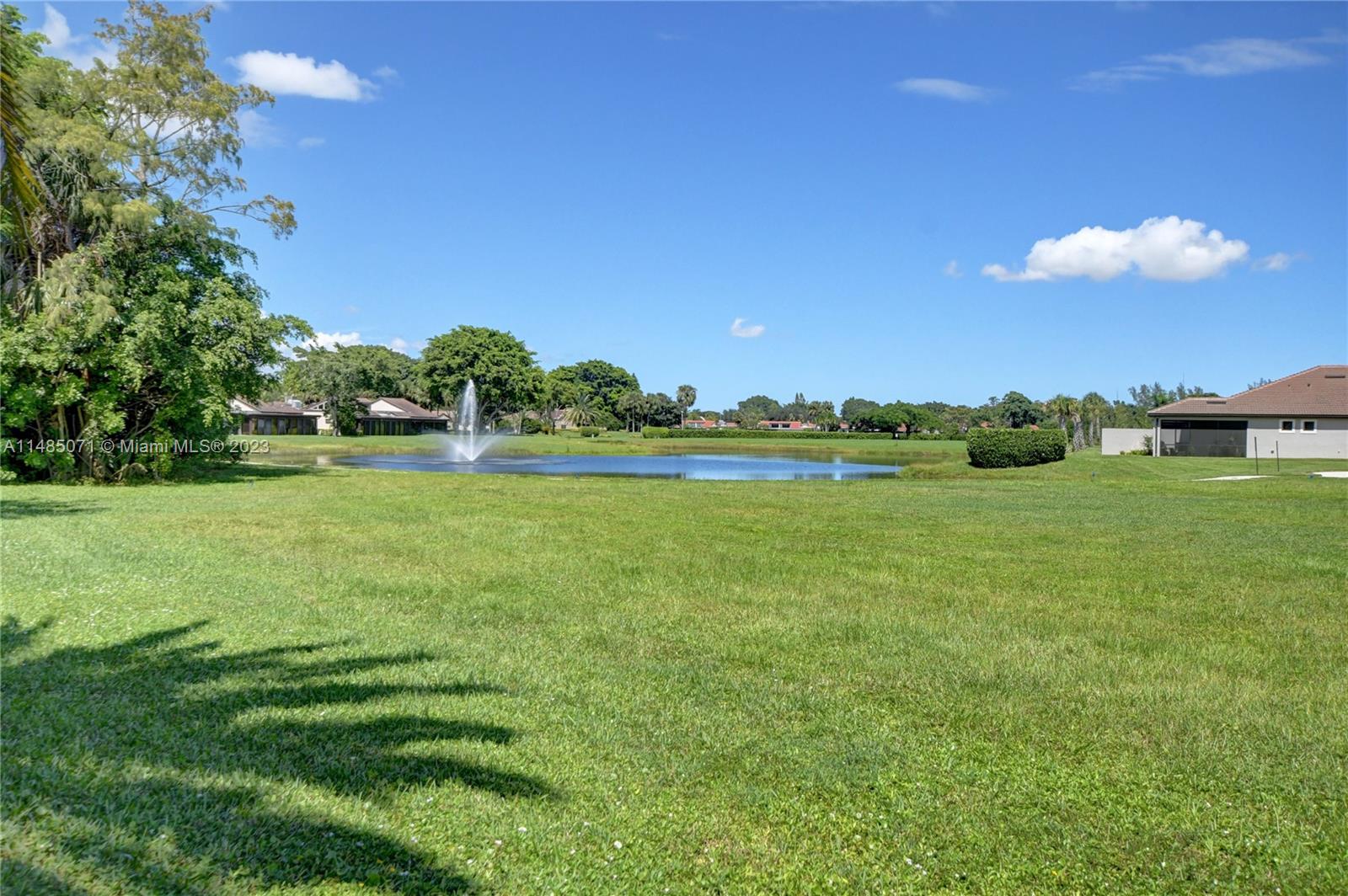 9264 Vista Del Lago, Unit E Boca Raton, FL 33428 - Photo 3 of 26 a yard with lots of green space and trees in the background