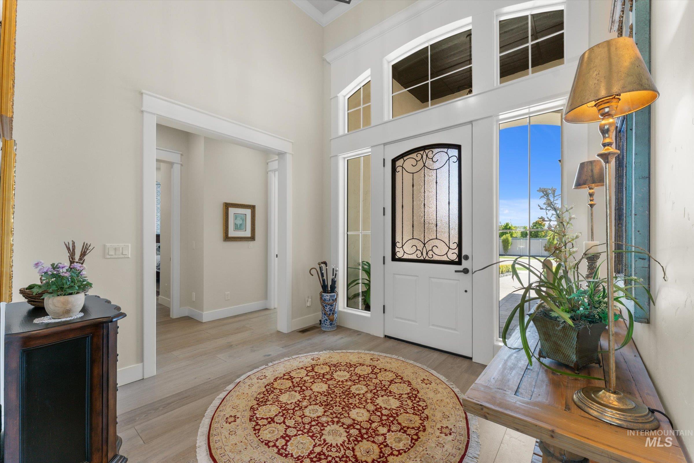 6585 South Pemberley Way Meridian, ID 83642 - Photo 7 of 43 Grand entryway featuring a soaring ceiling, wood-finish flooring, a decorative glass entry door with sidelights, and transom windows