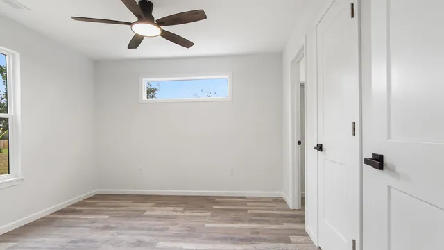 an empty room with wooden floor and ceiling fan