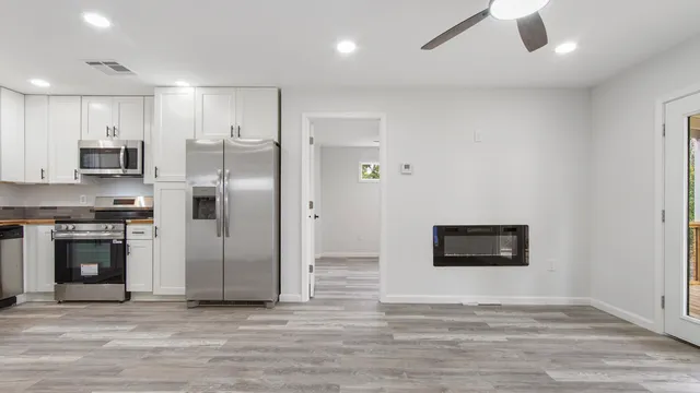 a room with stainless steel appliances kitchen island granite countertop a refrigerator and a stove top oven