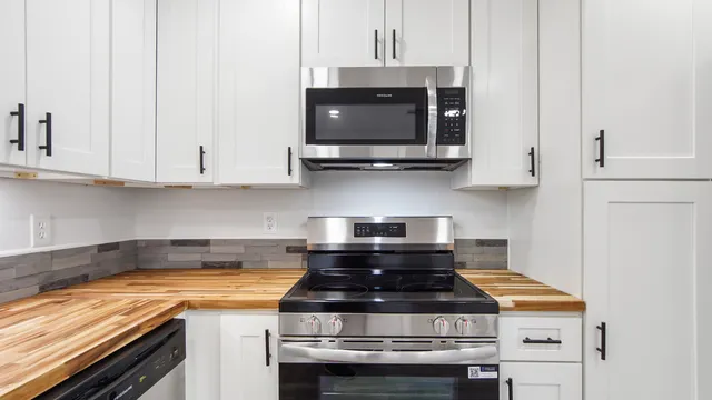 a kitchen with stainless steel appliances granite countertop white cabinets and a stove top oven with granite countertops