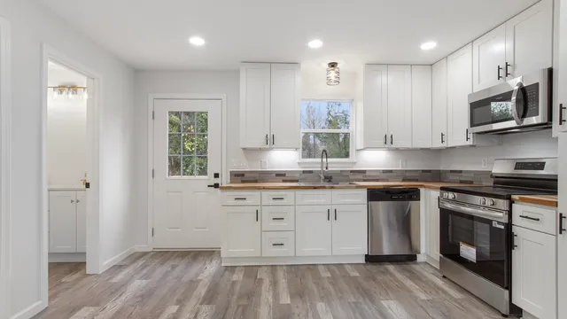 a kitchen with stainless steel appliances granite countertop a stove a sink and a microwave