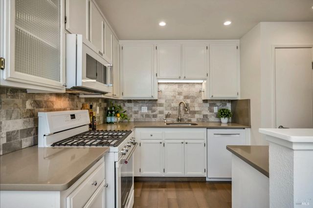 a kitchen with granite countertop a sink stove and cabinets