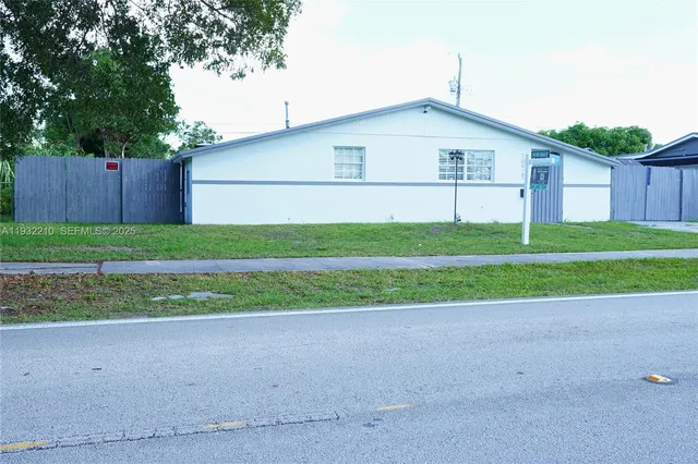 a view of a house with a yard and a large parking space