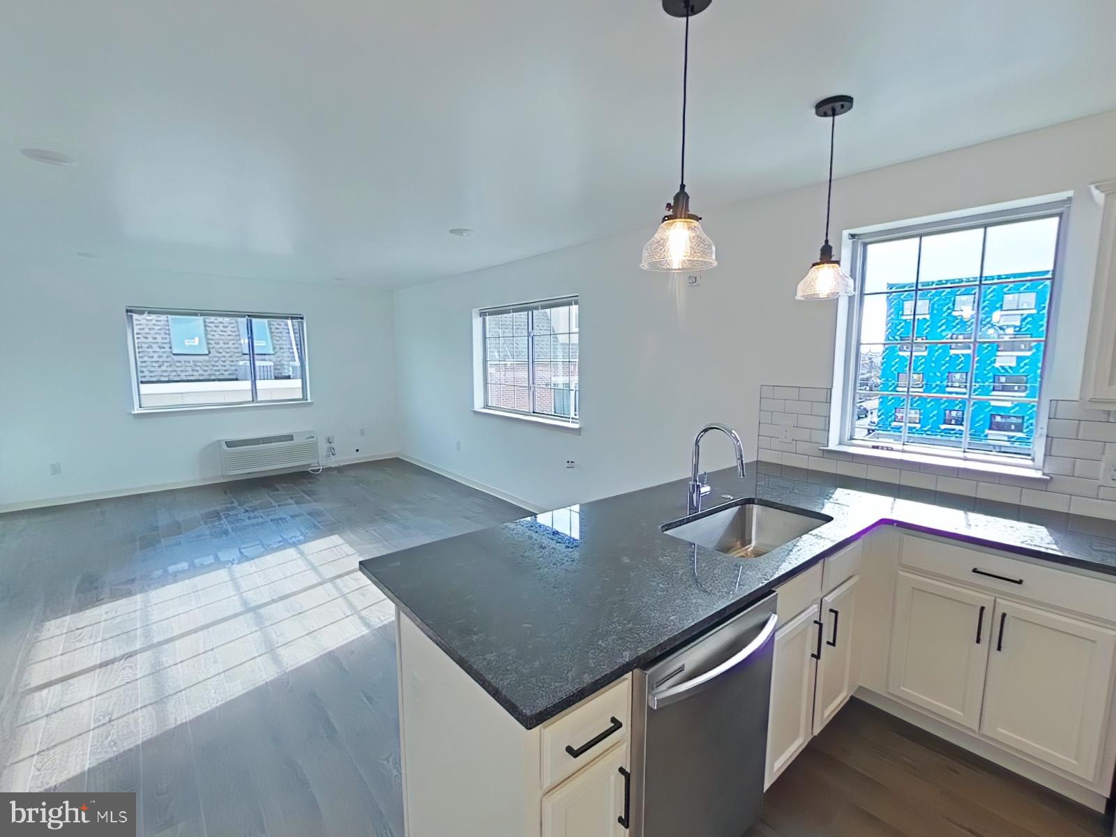 6649 Ridge Avenue, Unit C104 Philadelphia, PA 19128 - Photo 1 of 7 a kitchen with stainless steel appliances granite countertop a sink a stove a dining table and chairs
