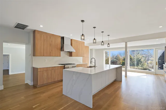 a large white kitchen with a large window a sink and stainless steel appliances