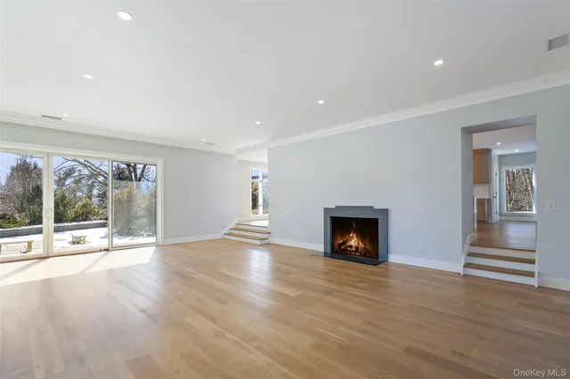 an empty room with wooden floor fireplace and windows