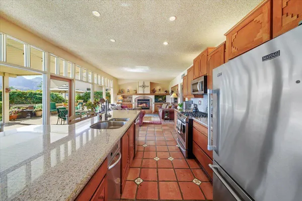 a view of a kitchen with kitchen island a large window a sink and stainless steel appliances