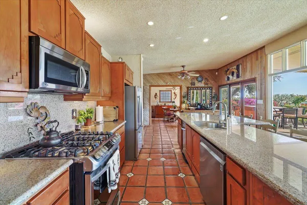 a kitchen with stainless steel appliances granite countertop a stove top oven a sink a counter space and cabinets