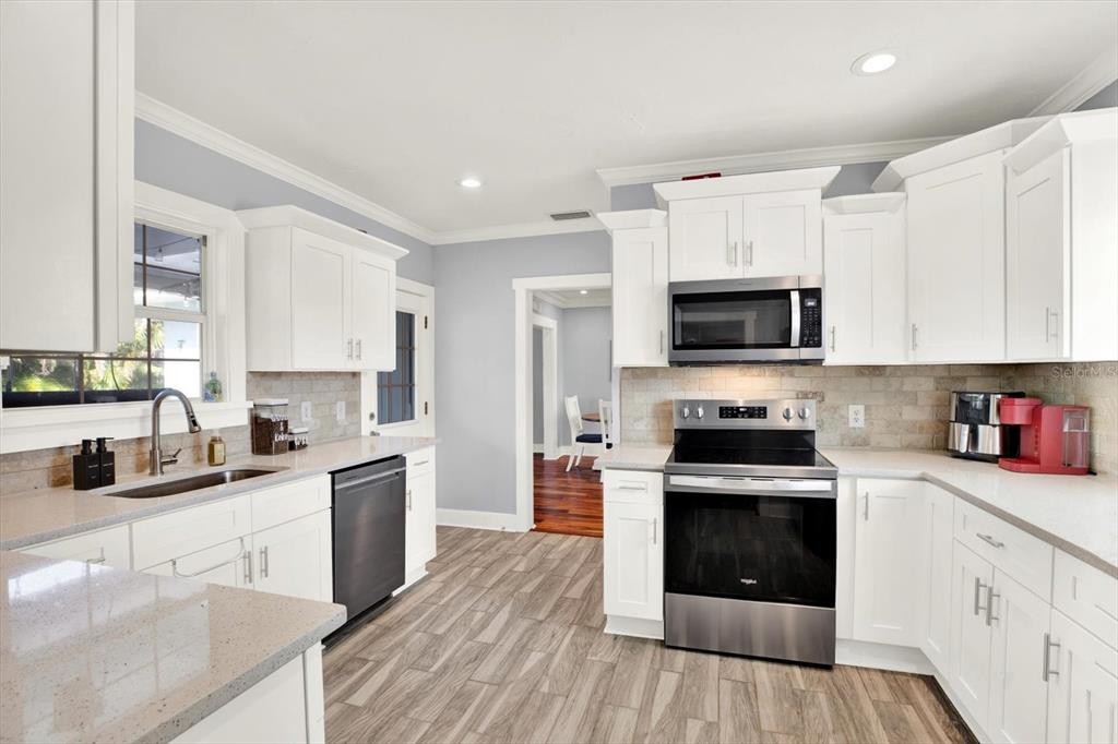 15656 1st Street East Redington Beach, FL 33708 - Photo 6 of 32 a kitchen with stainless steel appliances granite countertop a stove top oven a sink dishwasher and a refrigerator with wooden floor