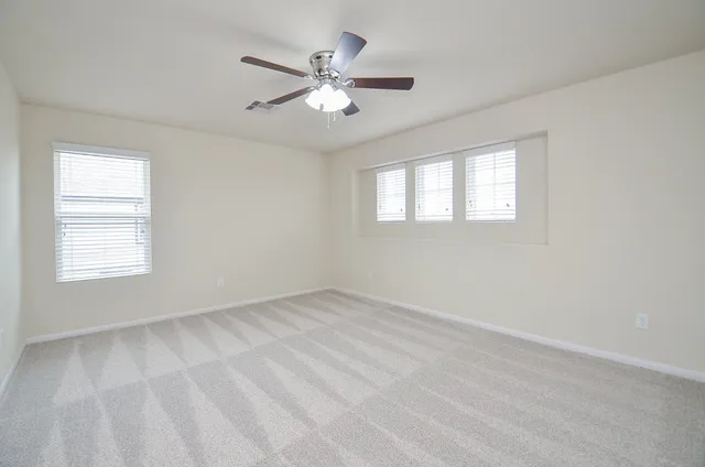 an empty room with windows and fan