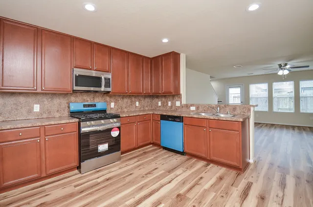 a kitchen with granite countertop wooden cabinets a stove top oven a granite counter space and a window