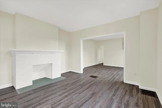 an empty room with wooden floor and a fireplace