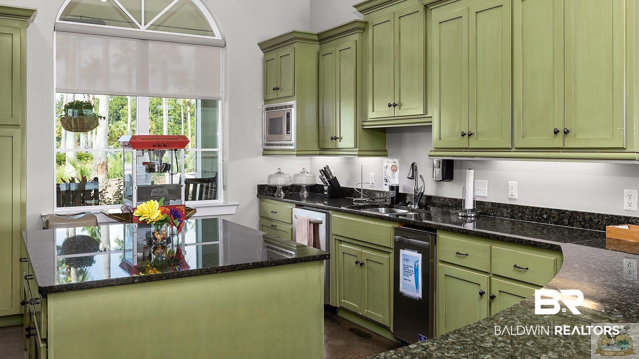 12489 Gateway Drive Elberta, AL 36530 - Photo 20 of 55 Kitchen with a center island, dark stone countertops, a sink, stainless steel microwave, and green cabinetry