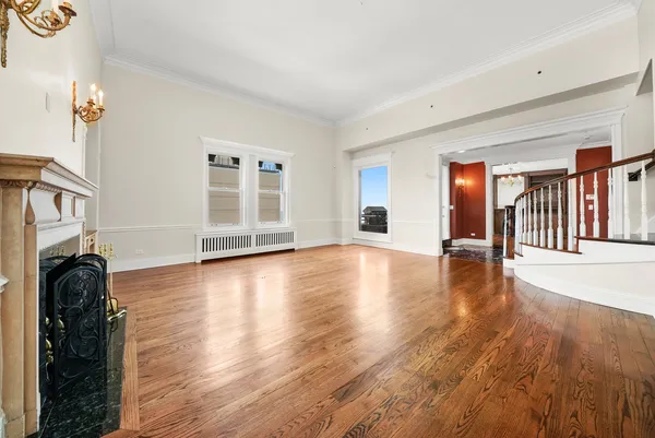 an empty room with wooden floor chandelier and windows