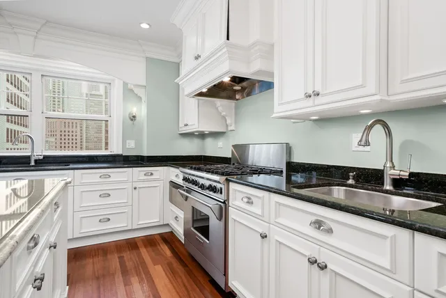 a kitchen with granite countertop white cabinets stainless steel appliances and a sink