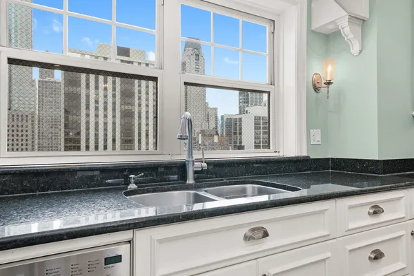 a large kitchen with granite countertop a white stove top oven and white cabinets