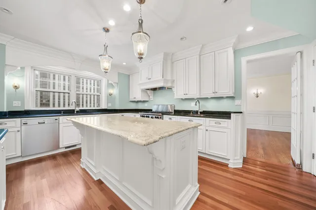a kitchen with stainless steel appliances white cabinets and a wooden floor