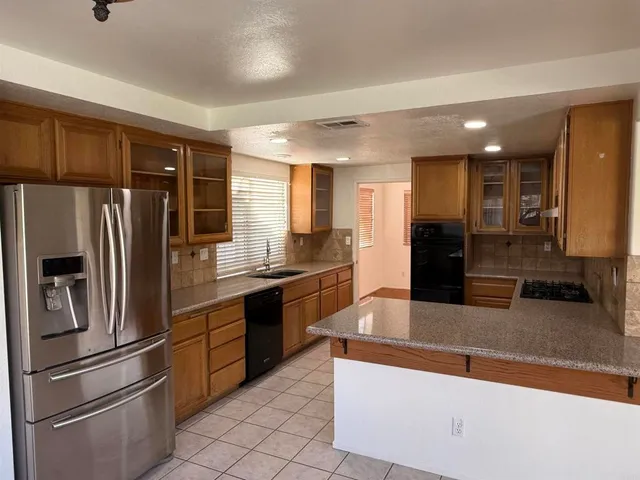a large kitchen with stainless steel appliances granite countertop a refrigerator and a sink