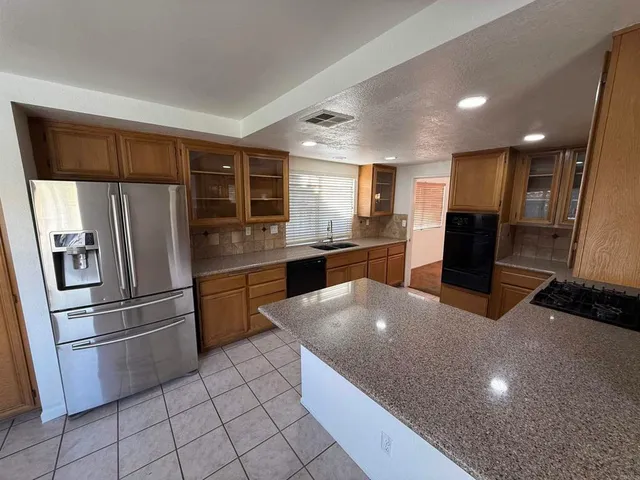 a kitchen with stainless steel appliances granite countertop a refrigerator and a sink