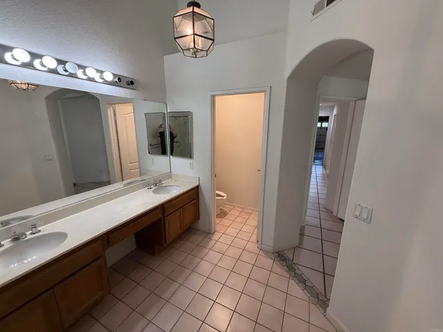 a large bathroom with a double vanity sink a toilet a mirror and shower