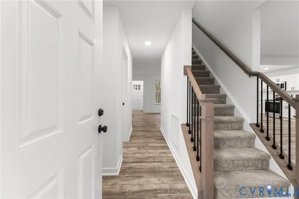 a view of a hallway with wooden floor and stairs