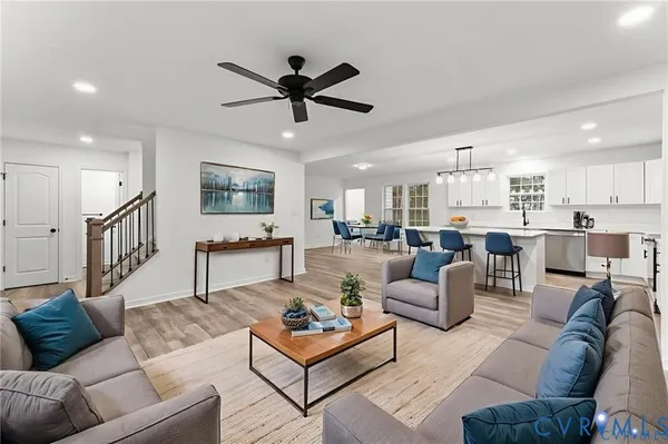 a living room with furniture kitchen view and a wooden floor