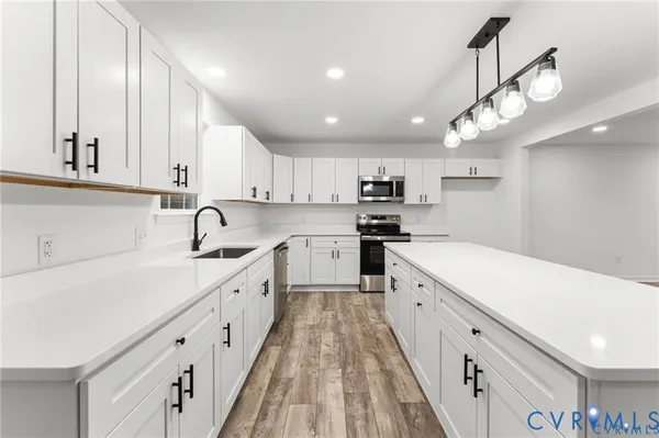 a large white kitchen with lots of counter space a sink and stainless steel appliances