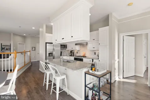 a kitchen with stainless steel appliances kitchen island granite countertop a table chairs stove and white cabinets