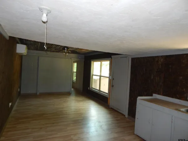 a view of an empty room with window and wooden floor
